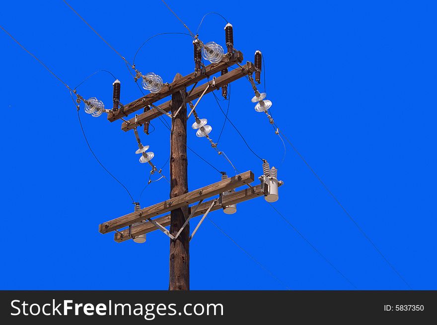 Wooden pillar with electric wires over blue sky