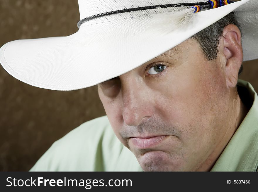 Man beneath a white cowboy hat in front of a gold background. Man beneath a white cowboy hat in front of a gold background