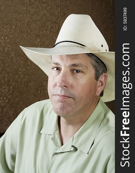 Man wearing a white cowboy hat in front of a gold background. Man wearing a white cowboy hat in front of a gold background