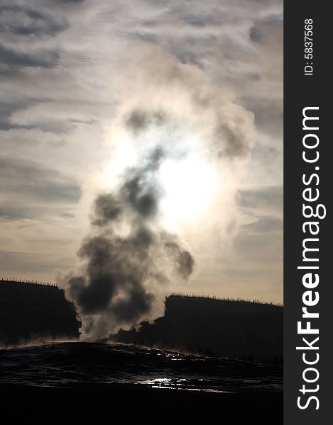 Old Faithful Geyser silhouetted at sunset - Yellowstone National Park. Old Faithful Geyser silhouetted at sunset - Yellowstone National Park.