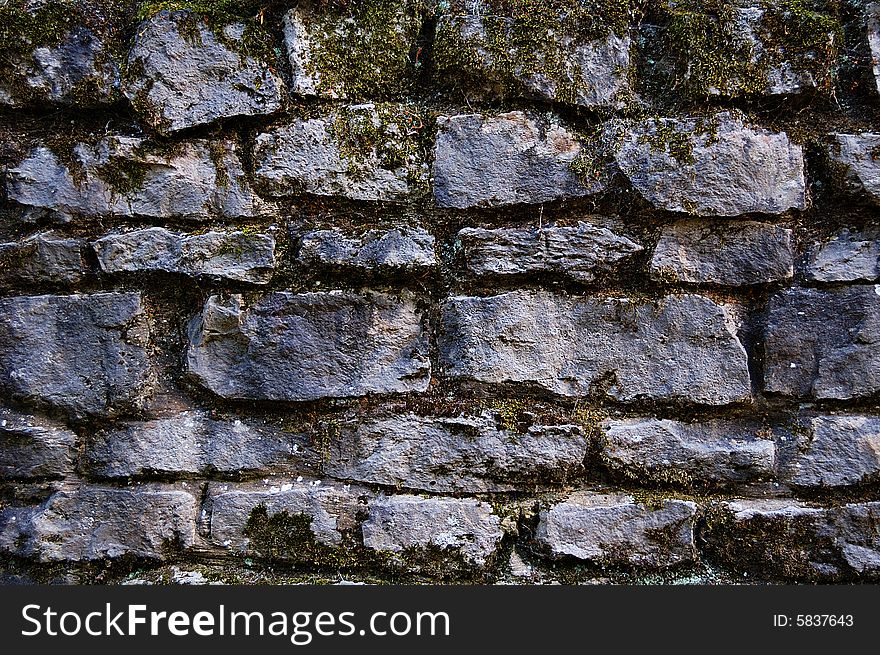 Old stones wall covered with moss and vegetation