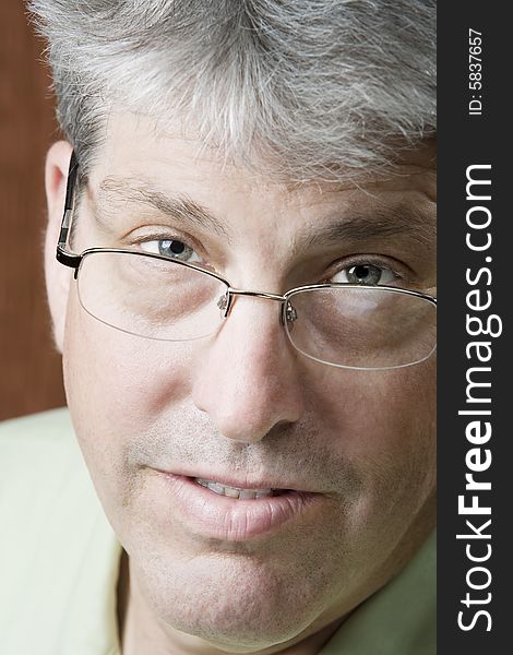 Man looking over glasses in front of a gold background. Man looking over glasses in front of a gold background