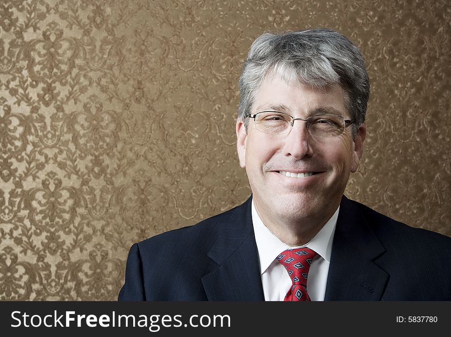 Corporate executive smiling broadly in front of a gold background. Corporate executive smiling broadly in front of a gold background