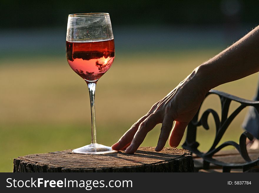 Woman reaches for glass of wine at sunset overlooking country. Woman reaches for glass of wine at sunset overlooking country.
