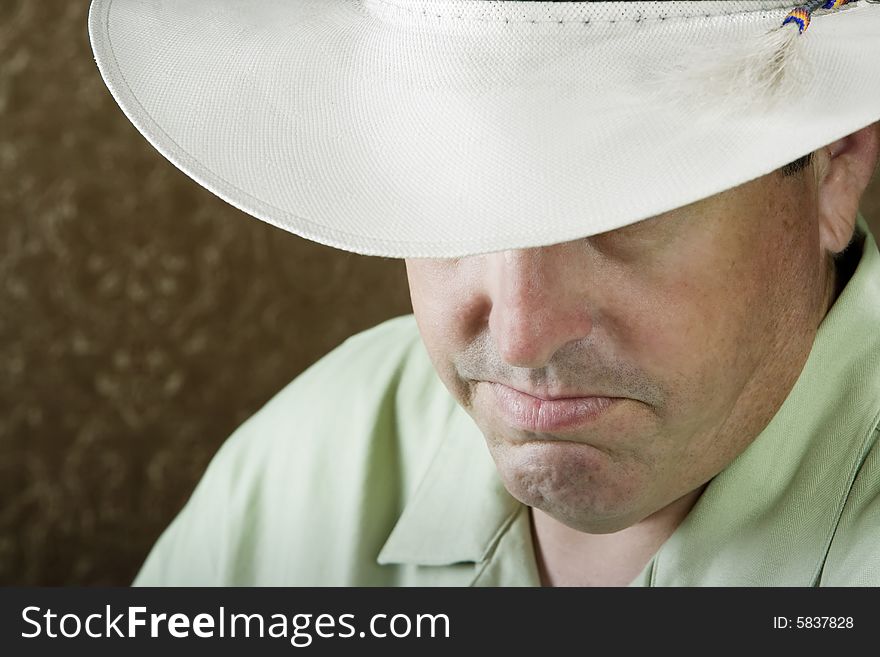 Man beneath a white cowboy hat in front of a gold background. Man beneath a white cowboy hat in front of a gold background