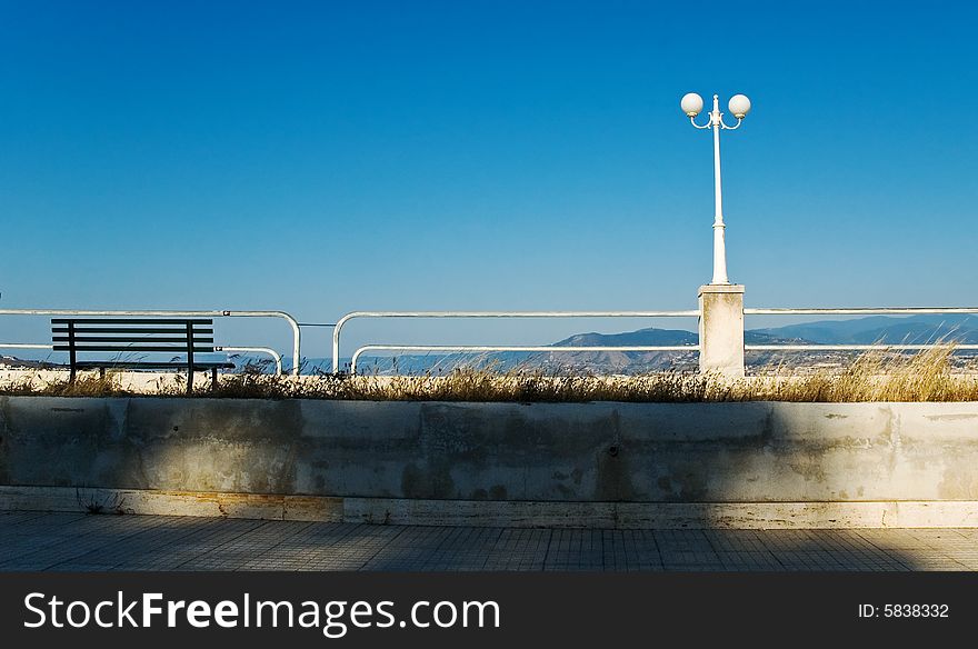 Bench and street light on the waterfront with blue sky and copy space