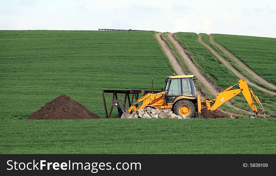 Excavator in the green field