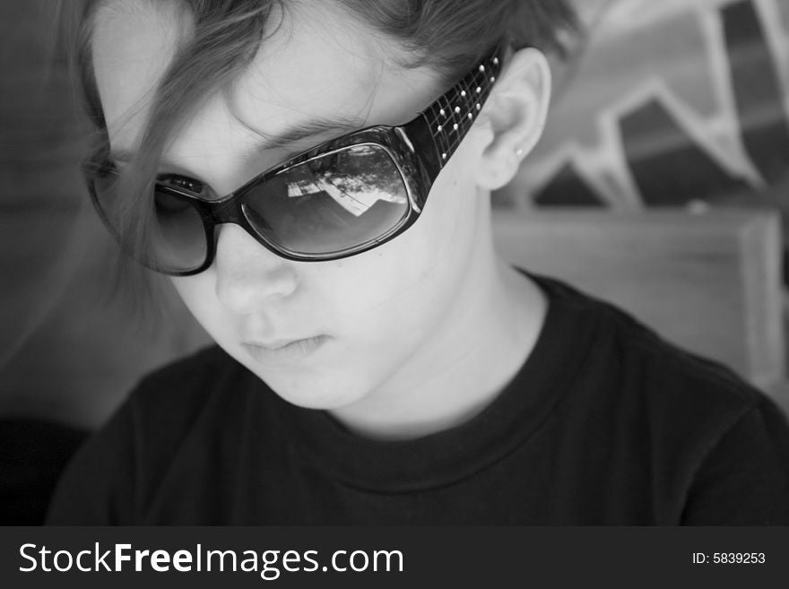 Ten year old girl glaring at the camera wearing black sunglasses. Ten year old girl glaring at the camera wearing black sunglasses.