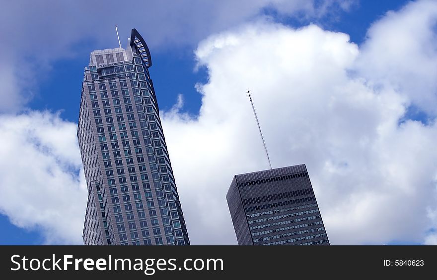 Two tall buildings against a blue sky with puffy clouds. Two tall buildings against a blue sky with puffy clouds.