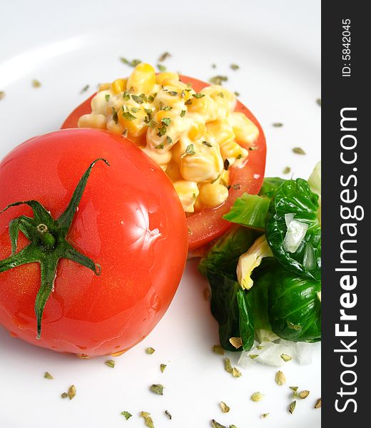 Tomato Stuffed with corn and 	
mayonnaise on a white dish