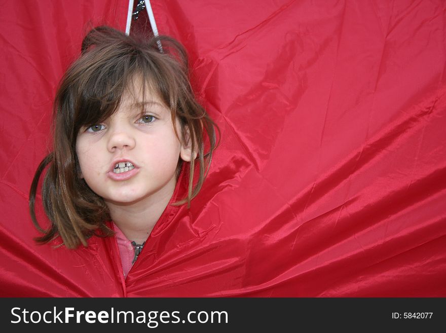 Young girl looking out of a red tent. Young girl looking out of a red tent.