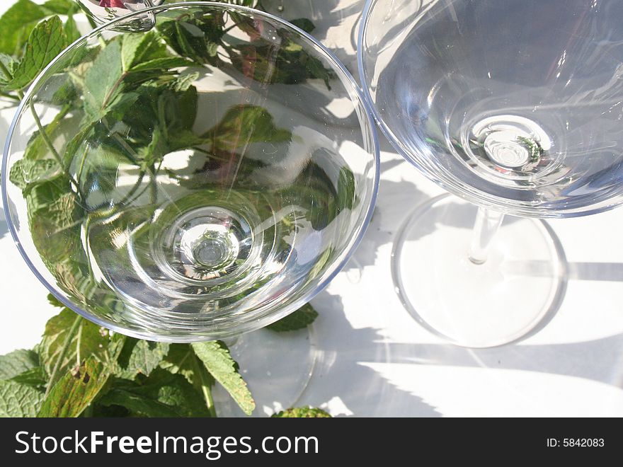 Two martini glasses with mint leaves surrounding on a white backround. Two martini glasses with mint leaves surrounding on a white backround.