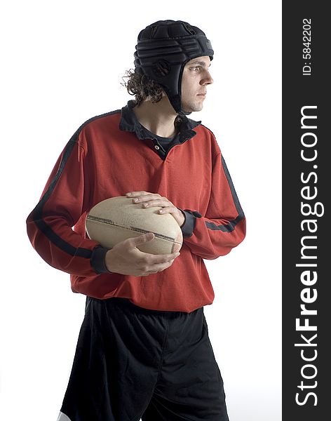 A young man, stands in a rugby outfit, holding on to the ball with both hands, looking away. Vertically framed shot. A young man, stands in a rugby outfit, holding on to the ball with both hands, looking away. Vertically framed shot.