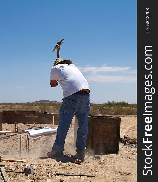 A construction worker is working on an excavation site. He is about to swing a pickaxe into the ground. Vertically framed shot. A construction worker is working on an excavation site. He is about to swing a pickaxe into the ground. Vertically framed shot.