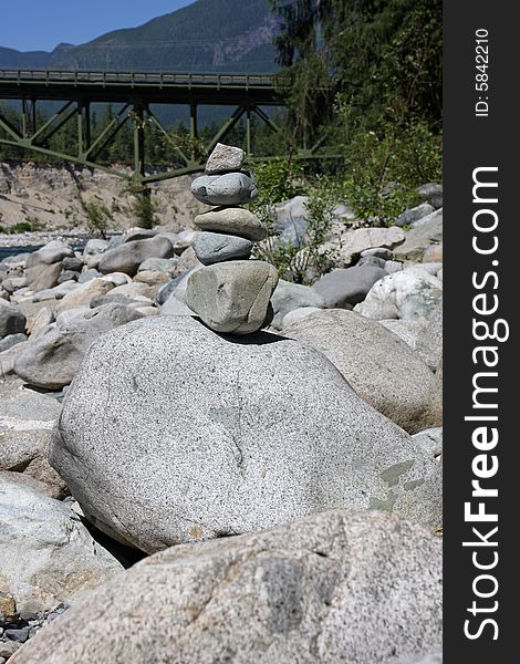 A scenic outdoor setting with five rocks perfectly stacked and balanced on one large boulder. A scenic outdoor setting with five rocks perfectly stacked and balanced on one large boulder.