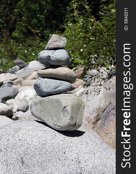Five various sized rocks stacked and balanced on a large boulder. Five various sized rocks stacked and balanced on a large boulder.
