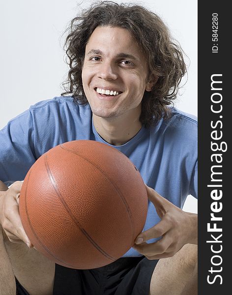 Smiling man sitting and holding a basketball. Vertically framed photograph. Smiling man sitting and holding a basketball. Vertically framed photograph