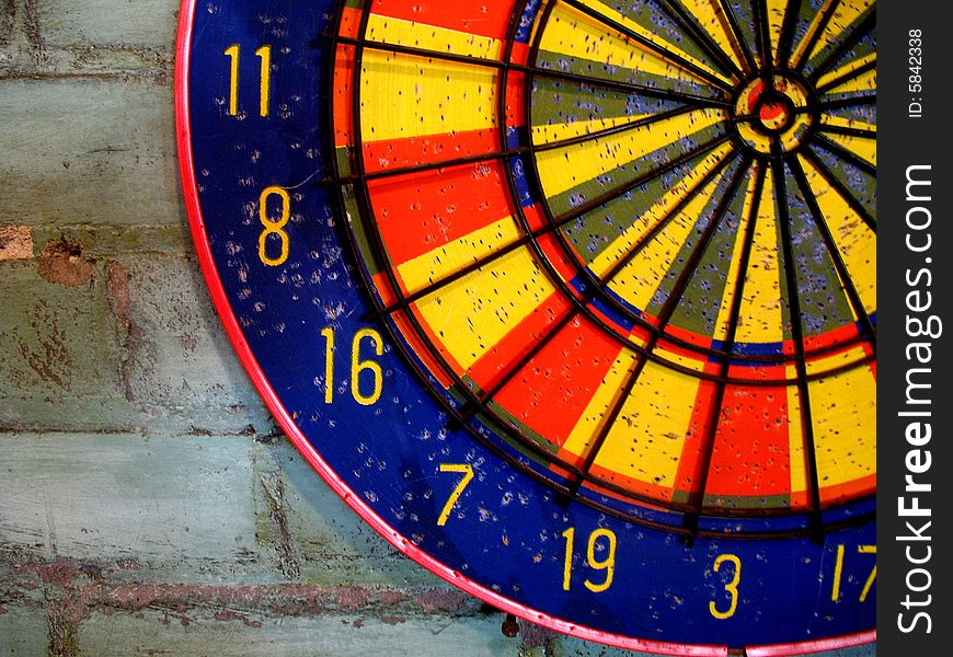 A colorful dartboard is displayed on a brick wall.  Horizontally framed photo. A colorful dartboard is displayed on a brick wall.  Horizontally framed photo.