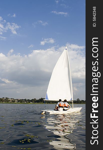 A woman and man are sailing on a lake.  Vertically framed shot. A woman and man are sailing on a lake.  Vertically framed shot.