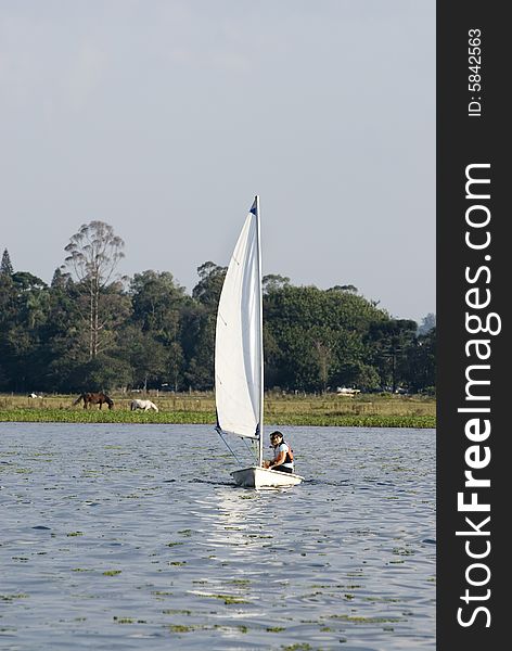 A couple is sailing together on a lake.  They are looking away from the camera.  Vertically framed shot. A couple is sailing together on a lake.  They are looking away from the camera.  Vertically framed shot.