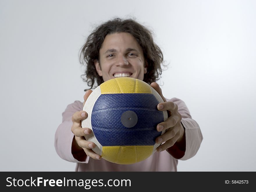 Man standing up holding a volleyball out in front of him and smiling at the camera.  Horizontally framed photo. Man standing up holding a volleyball out in front of him and smiling at the camera.  Horizontally framed photo.