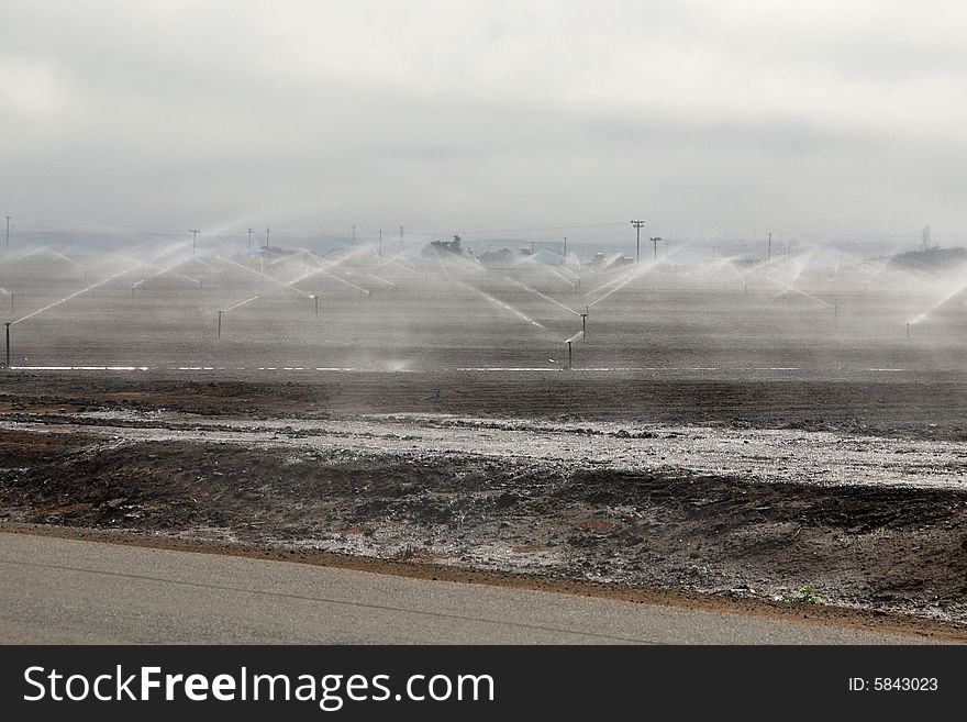 Sprinklers watering a large amount of farmland in california. Sprinklers watering a large amount of farmland in california
