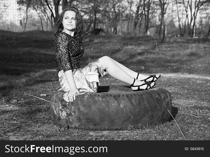 Portrait of young girl sitting on a motor-car tire in a park. Portrait of young girl sitting on a motor-car tire in a park