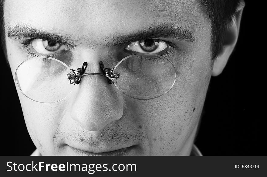 Face of young man in glasses on a black background