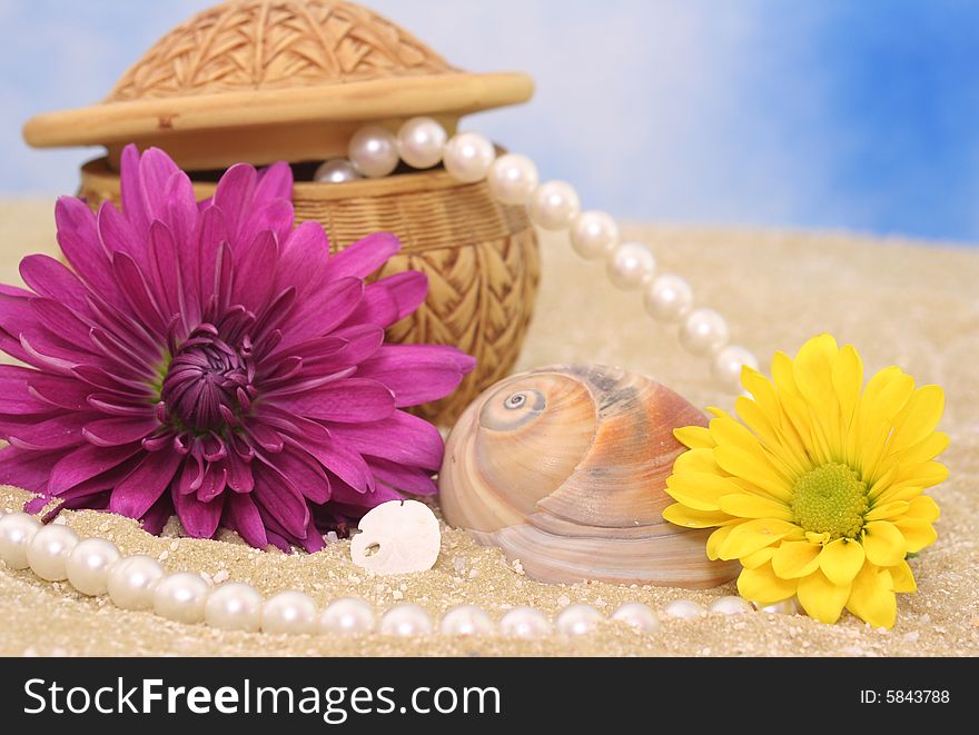 Flowers and Jewelry on Sand With Blue Background
