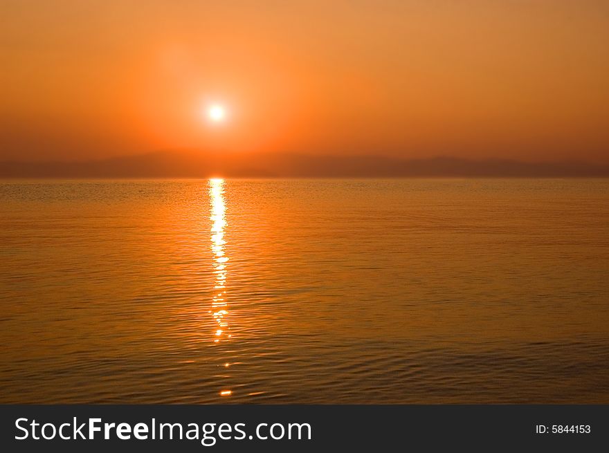 Orange sky, bright water and distant mountains. Orange sky, bright water and distant mountains