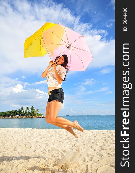 Smiling jumping girl on the beach with an umbrella. Smiling jumping girl on the beach with an umbrella.