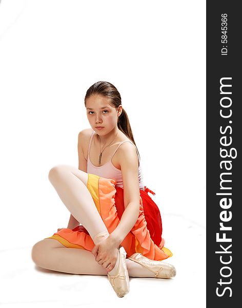 Young ballerina in rose dress sitting on the floor