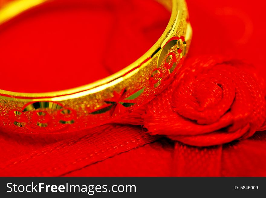 Close up of a golden ring beside the red rose ribbon. Close up of a golden ring beside the red rose ribbon.