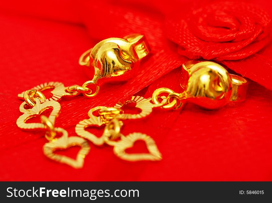 A pair of earrings beside the red rose ribbon. A pair of earrings beside the red rose ribbon.