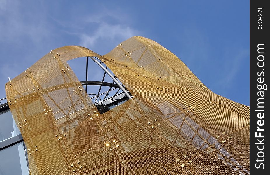 A part of modern building with golden net against blue sky. Den Haag, Holland. A part of modern building with golden net against blue sky. Den Haag, Holland