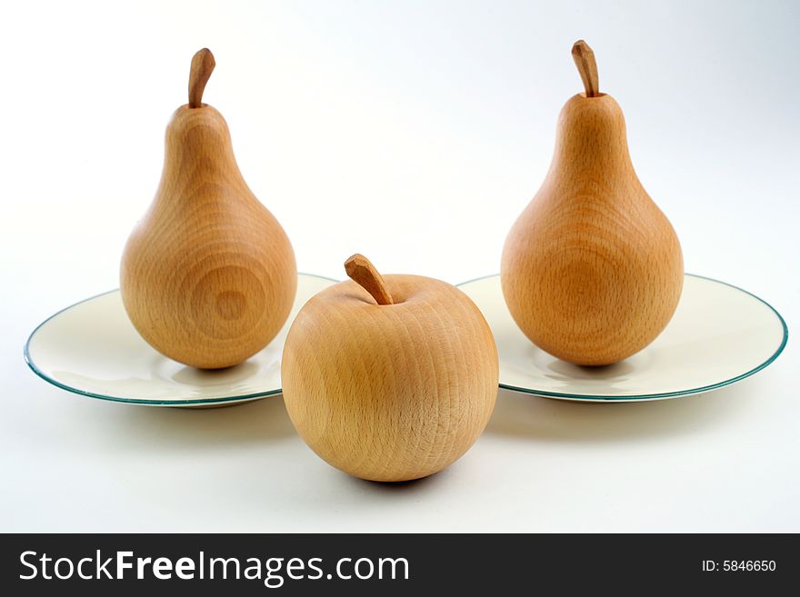 Wooden pears on plates with an apple. Wooden pears on plates with an apple