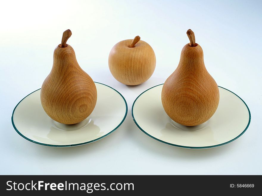 Wooden pears with an apple on plates. Wooden pears with an apple on plates