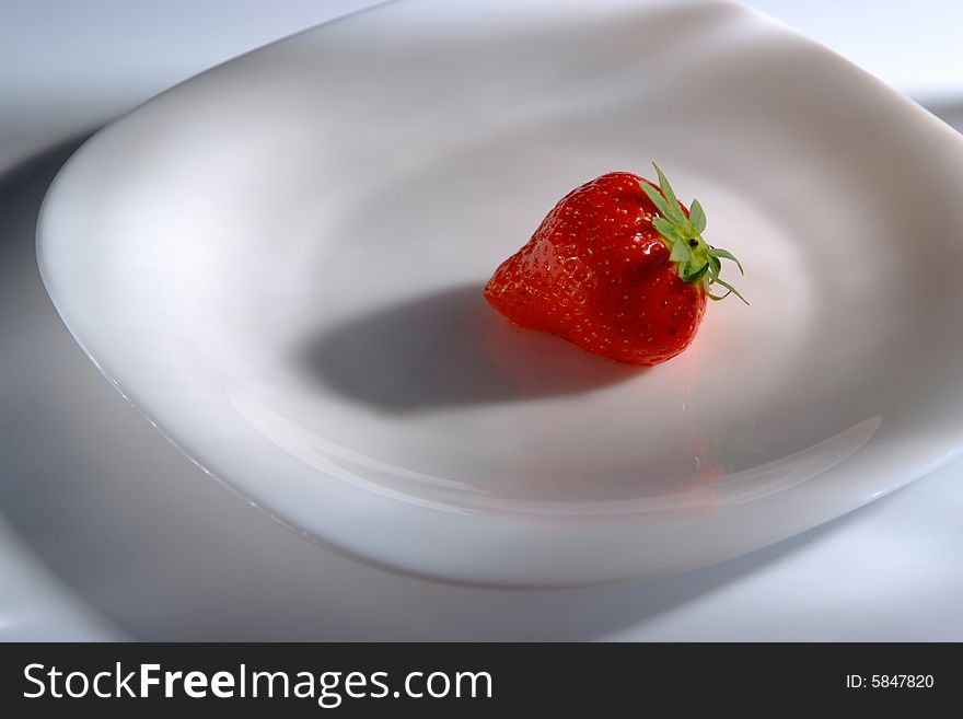 One strawberry on white plate