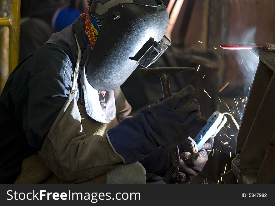 Welder with heavy protective clothing working on a steel construction. Welder with heavy protective clothing working on a steel construction.