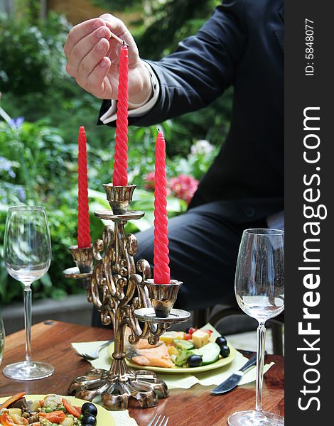 Person lighting red candle. Outdoors. Person lighting red candle. Outdoors