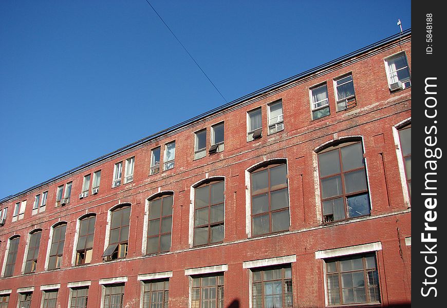 The old thrown Factory from a red brick greater glass windows on a background of the dark blue sky. The old thrown Factory from a red brick greater glass windows on a background of the dark blue sky