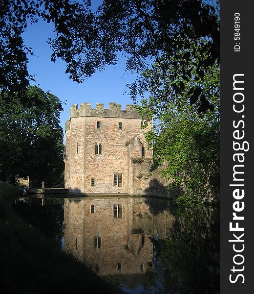 A tree framed image of a stone tower reflected in surrounding water. A tree framed image of a stone tower reflected in surrounding water.