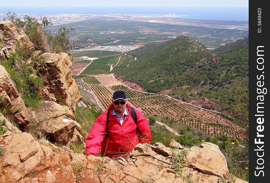 The man in red jacket in small mountains near the see. The man in red jacket in small mountains near the see