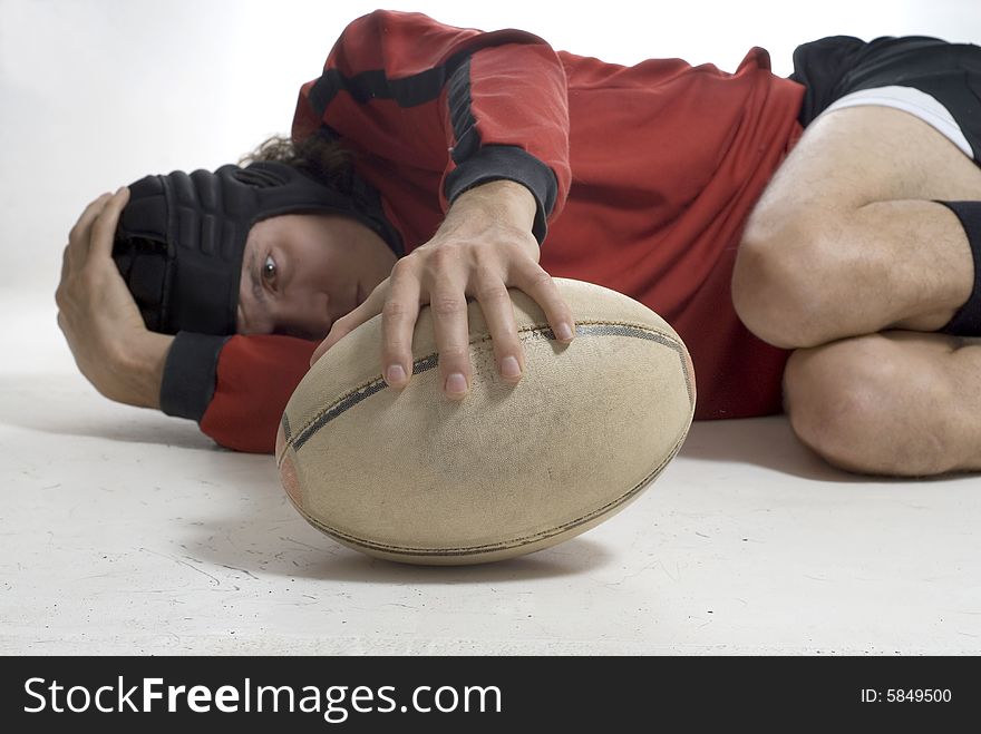 Rugby player curled up, holding a football, and looking at the ball.  Horizontally framed photo. Rugby player curled up, holding a football, and looking at the ball.  Horizontally framed photo.