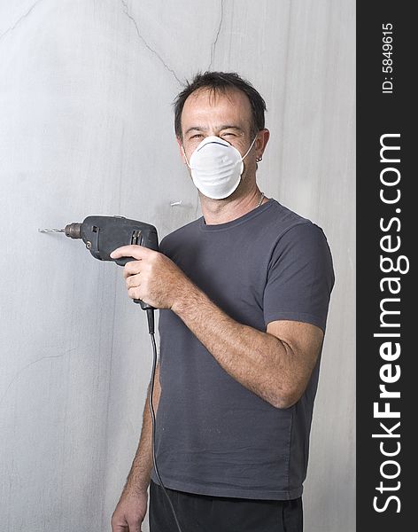 Man standing with mask holding drill and looking at camera. Vertically framed photo. Man standing with mask holding drill and looking at camera. Vertically framed photo