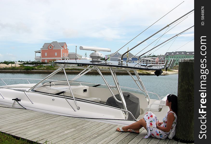 The girl sitting by the boat in Sandyport harbour (Nassau, The Bahamas). The girl sitting by the boat in Sandyport harbour (Nassau, The Bahamas).