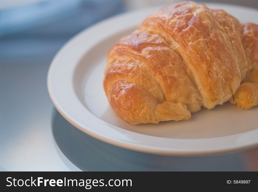 A gourmet fresh baked croissant, bathed in cool, elegant light. A gourmet fresh baked croissant, bathed in cool, elegant light.