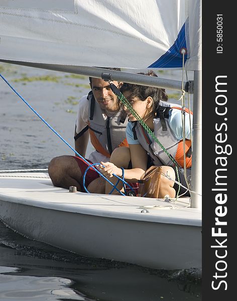 Man and woman sitting on sailboat holding rope for sail rigging. Vertically framed photo. Man and woman sitting on sailboat holding rope for sail rigging. Vertically framed photo