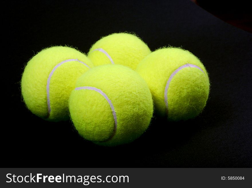 Four tennis ball on black background