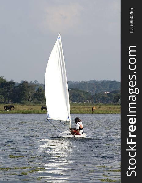 Couple sailing on sailboat in the distance. Sailing across lake. Vertically framed photo. Couple sailing on sailboat in the distance. Sailing across lake. Vertically framed photo